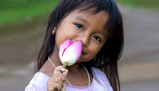 smiling young girl holding an unopened lotus flower