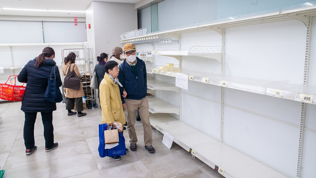 shoppers wearing Covid-masks in front of empty store shelves