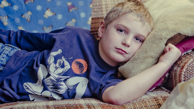 cranky-looking young boy laying on the couch