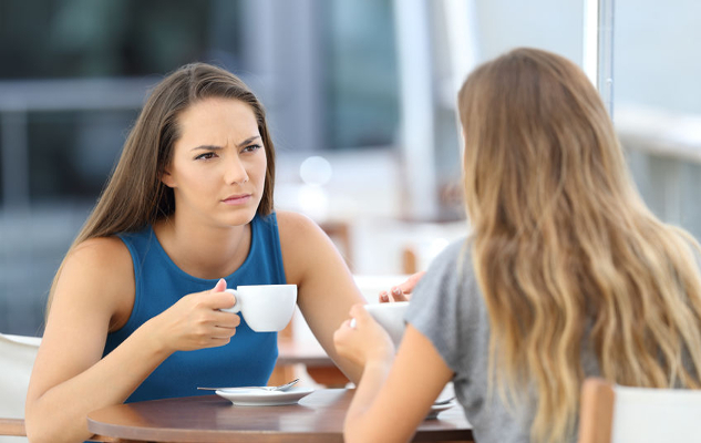 two women facing each other having coffee