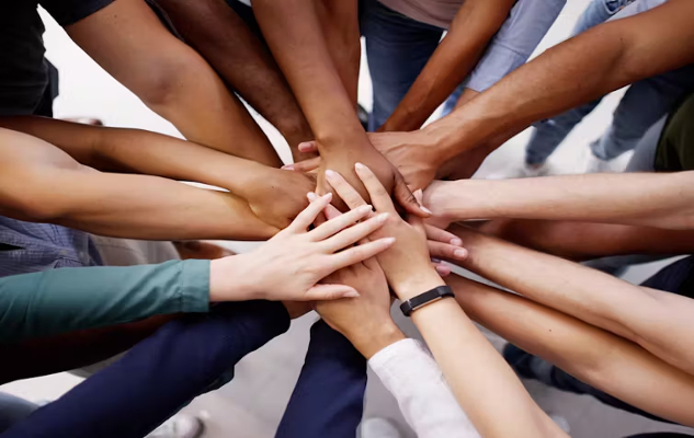 a circle of hands all piled up on top of each other in the center
