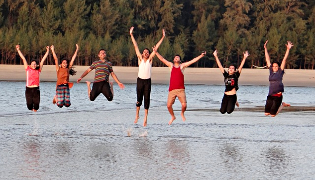 group of young adults in the middle of a river jumping with joy