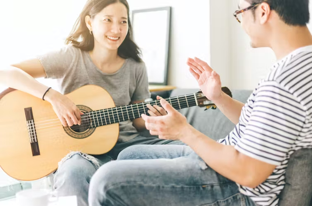 a woman playing guitar sitting in front of her partner
