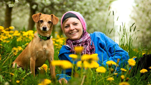 woman and dog laying down in a field of wild flowers